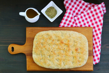 Delectable Italian Focaccia Bread with Dried Herbs on the Breadboard