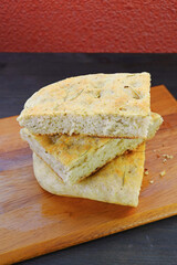 Stack of Freshly Baked Herbed Italian Focaccia Bread Slices on Wooden Breadboard