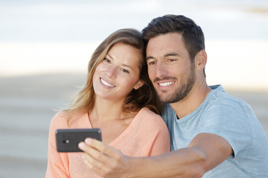 a loving couple makes selfie at sunset near the lake