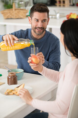man pouring orange juice from bottle into glass