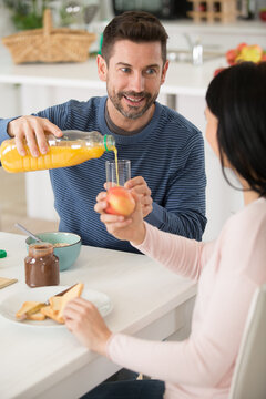 Man Pouring Orange Juice From Bottle Into Glass