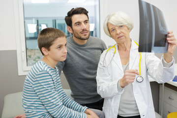 senior doctor showing xray to boy and dad