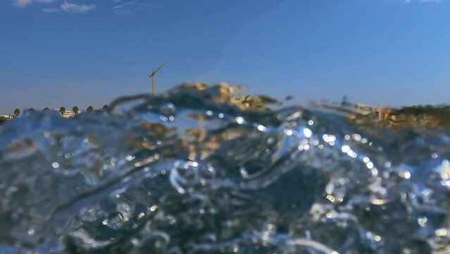 Unusual scene of Santa Maria di Leuca south Italian coast and cityscape saw from sailing boat moving along Ionian coast of Salento in Apulia, Italy. Low-angle water surface pov