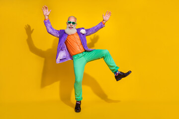 Obraz na płótnie Canvas Full length photo of cool impressed guy dressed violet velvet jacket rising hands dancing disco empty space isolated yellow color background