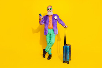 Full length portrait of positive grandfather hold use telephone suitcase isolated on yellow color...