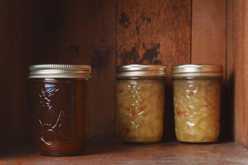 Preserved strawberry jam and relish in mason jars on rustic wood shelf