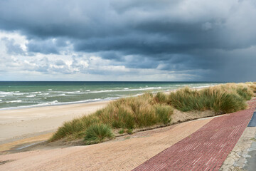 breakwater and marram grass over dunes and storm clouds at Malo-Les-Bains beach in Dunkirk, france