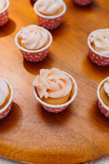 Gourmet cupcakes with white buttercream frosting and sprinkles on wooden background