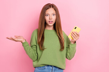 Portrait of adorable confused cute girl with long hairstyle dressed green sweatshirt hold...