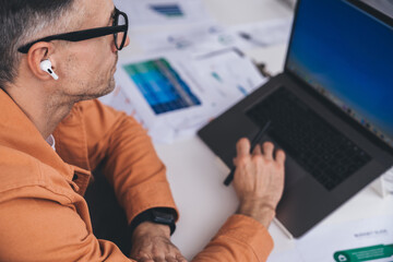 Serious male employee working on laptop at table