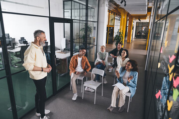 Multiracial coworkers looking at colleague during meeting in workspace
