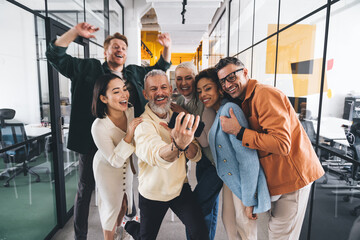 Fototapeta na wymiar Group of cheerful multiethnic friends taking selfie on smartphone near glass wall