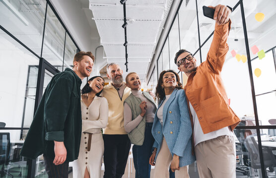 Group of diverse coworkers standing in office and taking self shot