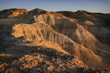 Fototapeta na wymiar Arid cliff in Valle de la Luna during golden hour, an arid desert landscape striking geological formations in semi-desert