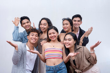 A group of seven close friends in their late teens to early 20s looking at the camera, smiling. Teamwork and unity concept. Isolated on a white backdrop.