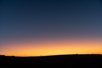 Background with landscape of an amazing and illuminated orange sunset in the blue sky, with a black base