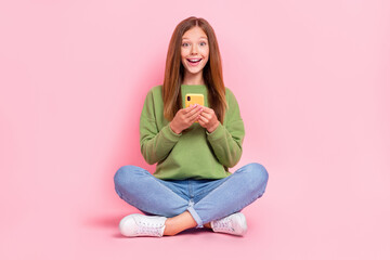 Obraz na płótnie Canvas Full length photo of funny excited school girl dressed sweatshirt typing twitter facebook telegram device isolated pink color background