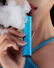 Close up of a beautiful girl with lips letting out smoke and smoking a vape