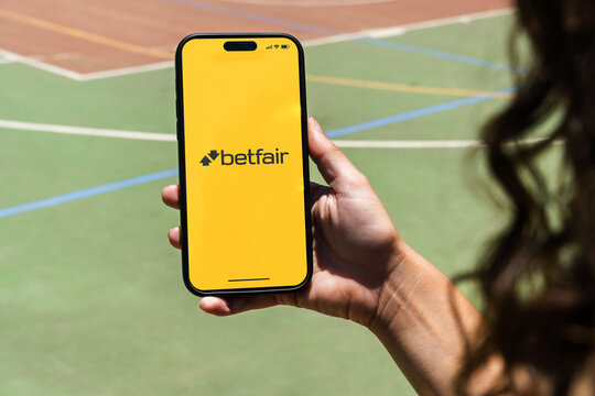 Girl holding an iPhone 14 Pro smartphone with Betfair betting provider app on screen. Multi-sport court in the background. Rio de Janeiro, RJ, Brazil. November 2022