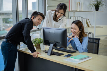 Asian call center team are looking at monitor screen and discussing about customer.