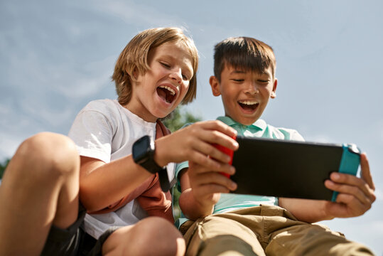 Boy look at friend play video game on game console