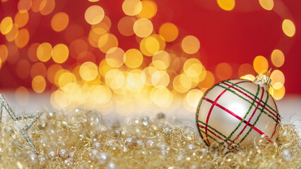 Christmas decoration on red. Gold Christmas ball on the snow front of the shiny background. 