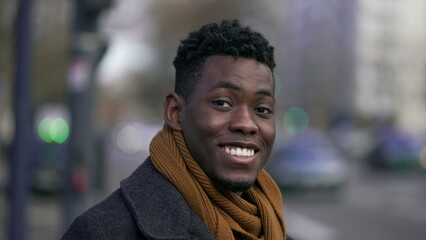 Happy black man smiling at camera standing outside in street looking at camera