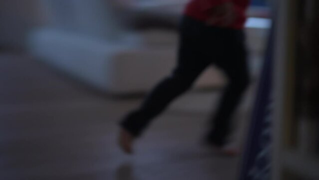 Blurred clip of one active child feet running indoors at home. Closeup excited kid runner at living room