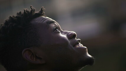 Meditative African man closing and opening eyes looking at sky smiling with FAITH and BELIEF