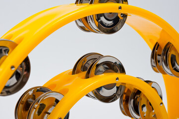 A tambourine with a plastic body and metal cymbals on a white background.