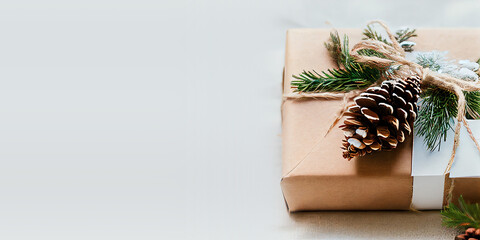 Christmas background with an eco-friendly packaged gift in craft paper and fir branches on white. Christmas Presents wrapped in gift paper. Zero waste Christmas holiday concept. Flat lay, copy space