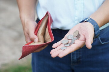 Closeup hand holds Thai baht coins and empty wallet. Concept, no money, economic crisis. Financial...