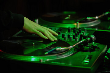 Hip hop dj scratches vinyl record on turntable. Disk jokey plays set with vinyls and sound mixer on...