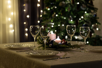 Serving the festive table. Food and drinks, plates and glasses. Evening lights and candles. Christmas dinner on Christmas Eve and New Year's Eve.