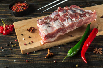 Fresh raw meat ribs on a kitchen cutting board with spices, seasonings and hot peppers. Cooking a delicious grilled lunch for a hotel or restaurant