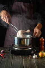 Cooking delicious broth from chicken legs and vegetables by the hands of a chef in the kitchen of a restaurant or hotel