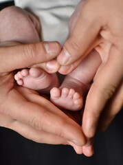 Obraz na płótnie Canvas feet of a newborn baby in the palms of mom and dad