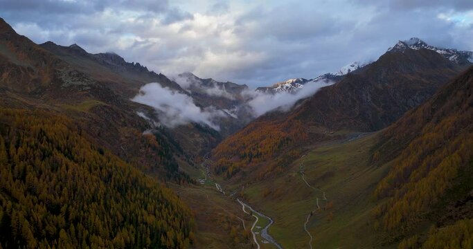 Stunning golden Casere woodland valley sunlight and cloud passing bottom of South Tyrol mountain Hyper lapse aerial view