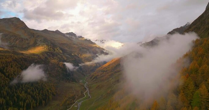 Stunning low cloud creeping through Casere Autumn forest South Tyrol valley at sunrise aerial view
