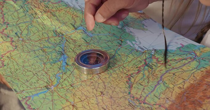 Close up of tourists looking at map, using compass, searching route together. Old man explaining, showing, teaching pointing with finger. Concept of tourism and hiking in hills.