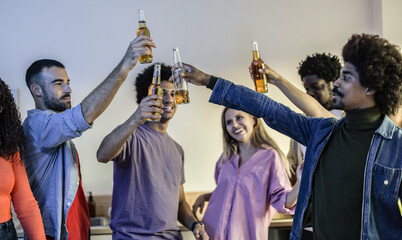 Multiracial group of friends toasting with bottles of beer at an apartment party