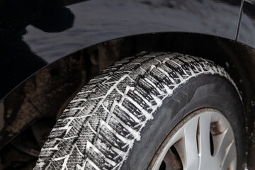 Close-up on a car wheel with winter tread tires with little wear during filming for a safe drive in...