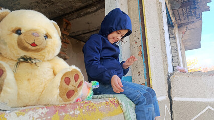 Consequences of the war in Ukraine. The child sits in a destroyed house. War in Ukraine. Children against war. Russian aggression against Ukraine. Destruction of Ukrainian infrastructure. 