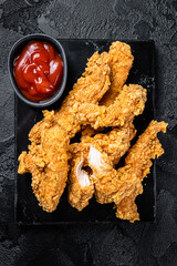 Breaded chicken strips  Fingers with  Ketchup. Black background. Top view