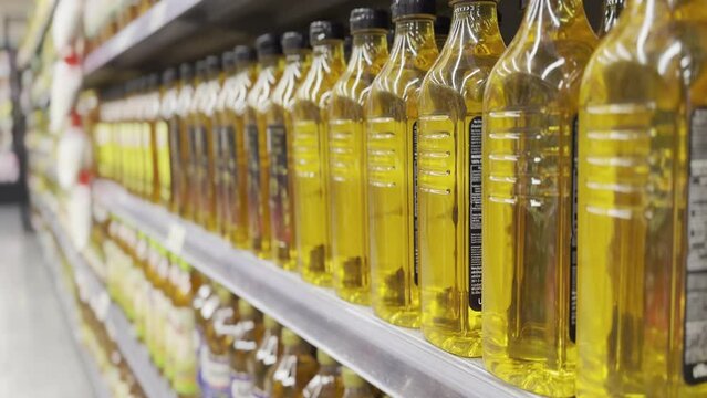 Rising prices cost of living global CPI index number surge up high in cooking extra virgin olive oil grocer market. Shelf in a row aisle showing food supply chain issues at retail store grocery mall.