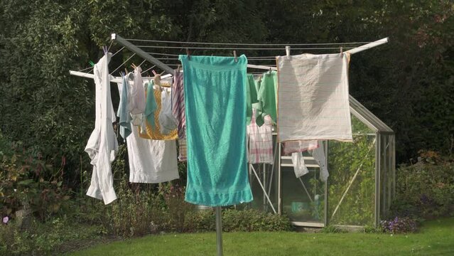 Clothes Hanging On Umbrella Clothesline Drying Rack Outside The House. - wide
