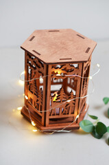 Golden lantern with burning candle standing on a metal tray, decorative lights as background. Festive season. Arabic home decor