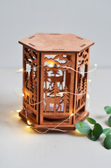 Golden lantern with burning candle standing on a metal tray, decorative lights as background. Festive season. Arabic home decor