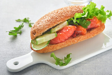 Sandwiches with salted salmon. Open sandwiches from cereal or whole grain rye bread with salted salmon, sesame seeds and dried tomato on white marble stand. Seafood. Healthy food. Scandinavian cuisine