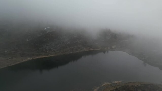 Mountain lake in the fog in the mountains. It's cold weather in the Alps. Aerial Shot